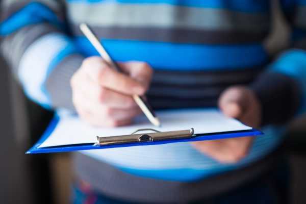 businessman holding a clipboard and write on it businessman holding a clipboard and write on it